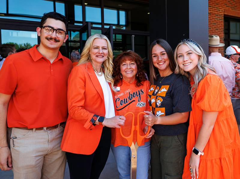 A group poses with scissors at the Agricultural Hall tailgate and ribbon cutting