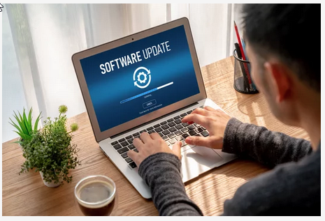 A person typing on a laptop computer with a ‘Software Update’ message displayed on the screen.